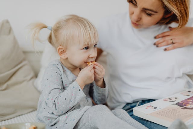 Bambina che mangia vicino a una donna.